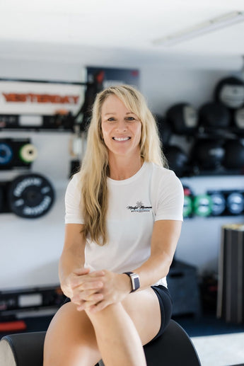 Female model wearing white MINDFUL MOVEMENT shirt while sitting inside store