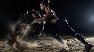 Woman pushing a large tire during an intense strength workout